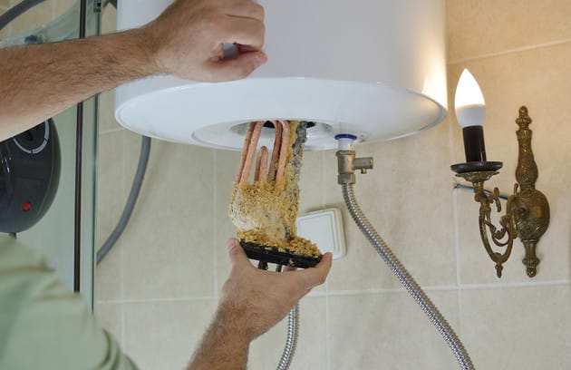 Technician removing mineral buildup from a water heater in Rome