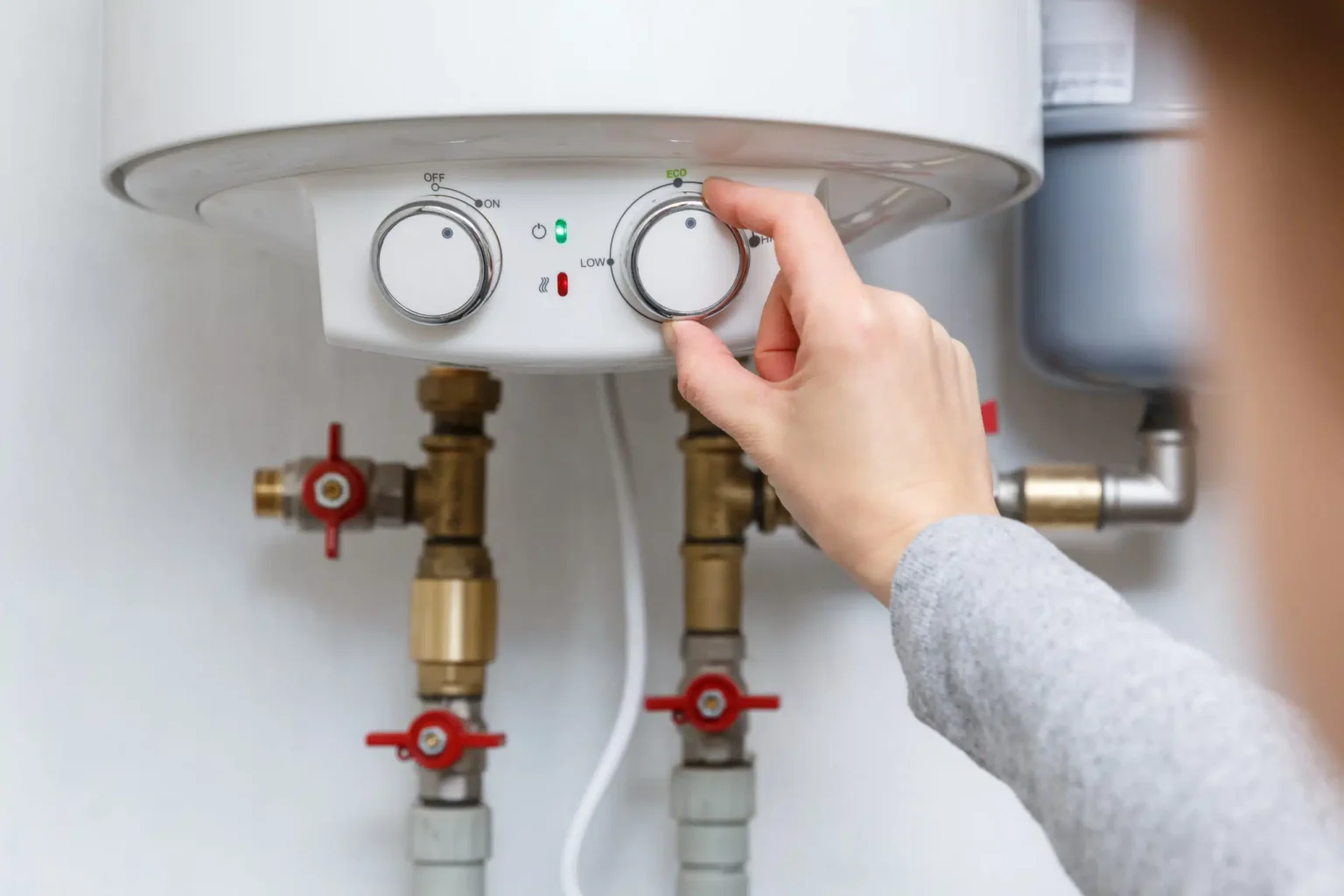 Homeowner adjusting the temperature controls on a water heater in Rome